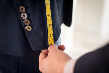 Tailor Taking Measurements For A Suit Fitting