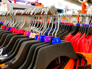 Fototapeta premium Different sized hanger with colourful dress size tags XL L M XS t shirts displayed in shop for sale