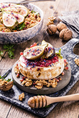 tasty healthy dish with figs fruits, nuts, honey, camembert cheese, couscous and pomegranate seeds and figs