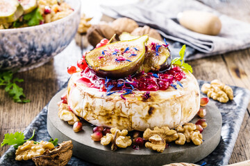 tasty healthy dish with figs fruits, nuts, honey, camembert cheese, couscous and pomegranate seeds and figs