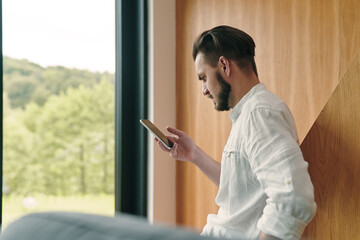 Portrait of young businessman holding smart phone and looking at screen