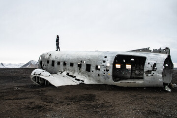 Woman standing on a plane wreck in southern Iceland