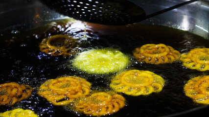 Jalebi an indian sweet dish being fried in sugar syrup in a large container