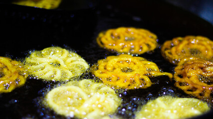Jalebi an indian sweet dish being fried in sugar syrup in a large container