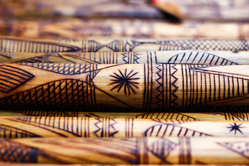 hand made wooden bamboo carving engraved fish figure artwork on bamboo, rows of engraved bamboo sticks. textured background. tribal artwork.