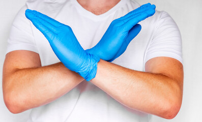 Obraz premium Male Doctor Hands Crossed make Stop Sign. Man in White T-shirt Wearing and Gloves Isolated on white background