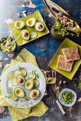 top view of organic raw green avocados sliced in halves with toasts on rustic table