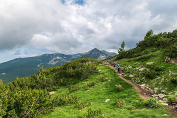 Two hikers in mountains with backpacks on sunny summer day.