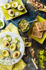 top view of organic raw green avocados sliced in halves with toasts on rustic table