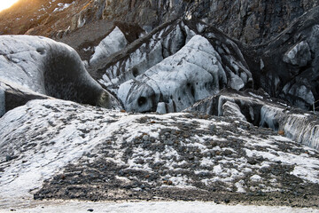 The opening to an ice cave in the Vatnajokull glacier in southern Iceland covered with snow and black dirt
