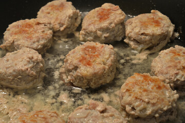 Meat cutlets are fried in frying pan.