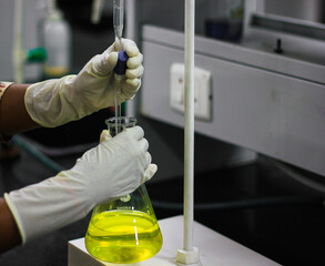 scientist holding albuminometer containing yellow solution with a cork a gloved hand in chemistry laboratory