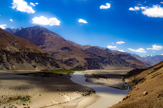 shades of cloud in High dynamic range image of barren mountain in a desert with river and deep blue sky in ladakh, Jammu and Kashmir, India