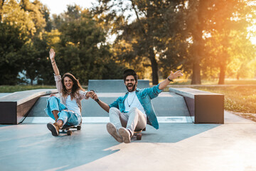 Beautiful young couple enjoying outdoors in city skateboarding park