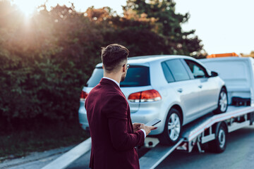 Elegant middle age business man calling towing service for help on the road. Roadside assistance...