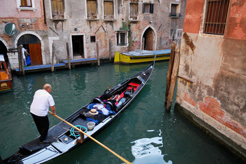 Fototapeta na wymiar Gondolier maneuvering his boat around a canal corner in Venice