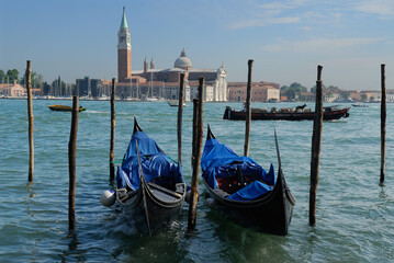 Fototapeta na wymiar Docked Gondolas and passing boats on Giudecca Canal Venice