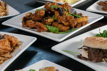Table full of delicious Mandarin food with plenty of plates to choose from with the Tangerine Chicken in the center.