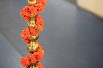 marigold flowers chain wrapped around brass lamp stand base.