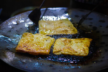 mughlai paratha, an indian street fast food is being fried in oil in a frying pan.