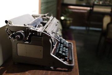A closeup image of an old vintage type writer on a table with eroded keys with selective focus on the handle background blur