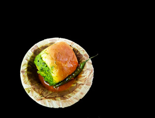 Vada pau bread and green sauce on a plate in dark background