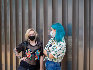 Mujeres jóvenes con mascarilla hablando respetando las medidas de seguridad y distanciamiento...