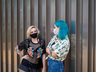 Mujeres jóvenes con mascarilla hablando respetando las medidas de seguridad y distanciamiento...