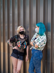 Mujeres jóvenes con mascarilla hablando respetando las medidas de seguridad y distanciamiento...