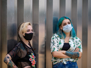 Mujeres jóvenes con mascarilla hablando respetando las medidas de seguridad y distanciamiento...