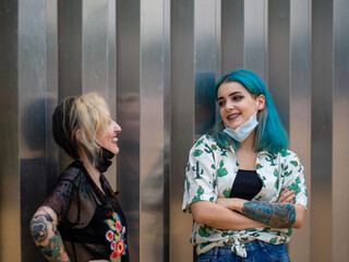 Mujeres jóvenes con mascarilla hablando respetando las medidas de seguridad y distanciamiento...