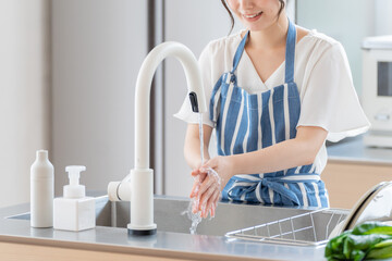 キッチンで手洗いをする女性 © taka