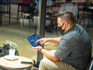 Hombre joven de negocios con tatuajes mirando las acciones de bolsa en su tablet