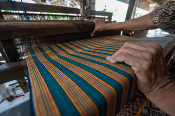 Fototapeta na wymiar Weaving a striated fabric (kain lurik) using traditional machine