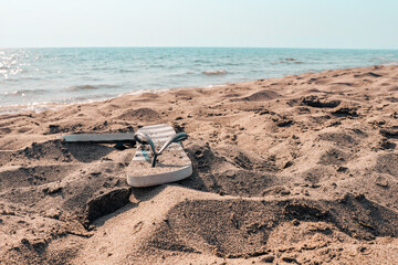 Fototapeta na wymiar Summer beach at the sea with flip-flops on a yellow sand