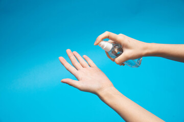 Spraying a hand sanitizer from a transparent mist spray bottle to the hand