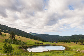 Fototapeta na wymiar Large pond in swampy meadow among rolling hills country side british columbia Canada