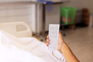 Patient hands using remote for adjustment level sick bed at hospital