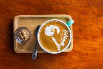 Cup pf hot flat white coffee  with brown sugar on wooden table in outdoor summer cafe 
