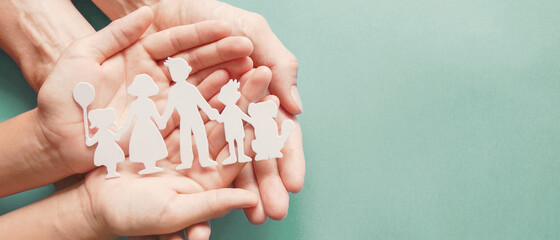 Adult and children hands holding paper family cutout, family home, adoption, foster care, homeless...