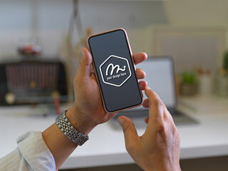 Male hands holding mock up smartphone in blurred worktable background