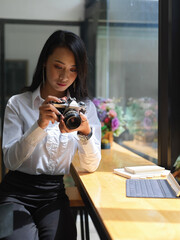 Female photo grapher checking photo on digital camera in studio