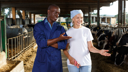 Portrait of two active employees working in cowshed on farm