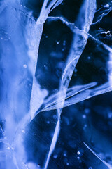 Detailed macro photo of Cracks and frozen bubbles on ice of deep lake in winter. Nature background.