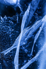 Detailed macro photo of Cracks and frozen bubbles on ice of deep lake in winter. Nature background.