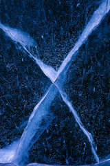 Detailed macro photo of Cracks and frozen bubbles on ice of deep lake in winter. Nature background.