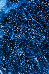 Detailed macro photo of frozen bubbles on ice of deep lake in winter in blue color. Nature background. Nature background.