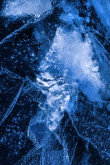 Detailed macro photo of Cracks and frozen bubbles on ice of deep lake in winter. Nature background.