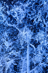 Detailed macro photo of Cracks and frozen bubbles on ice of deep lake in winter. Nature background.