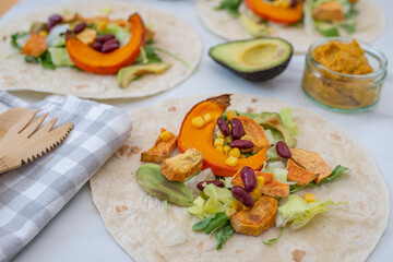Open vegan tortilla wraps with sweet potato, beans, avocado and pumpkin